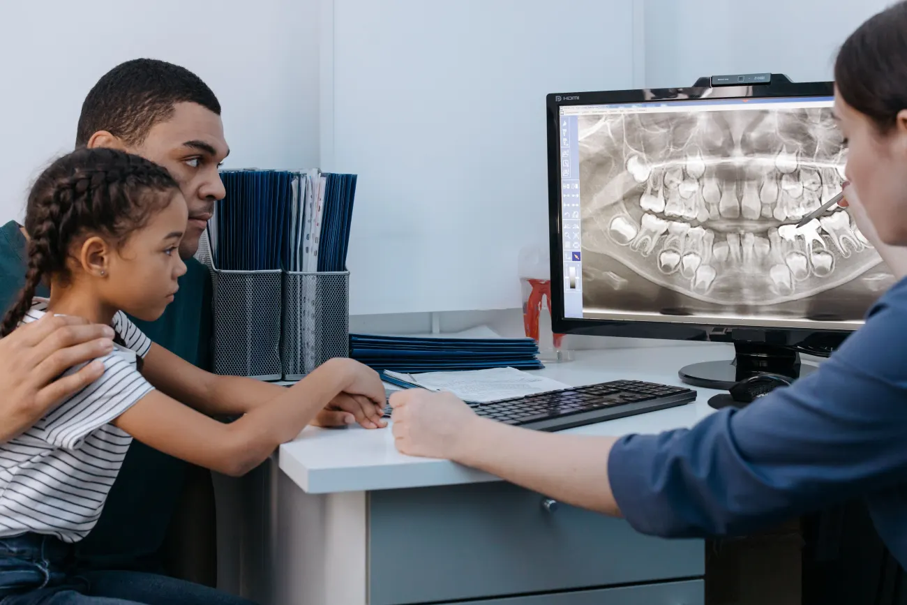 Parent and child discussing dental care with a dentist in a clinic setting